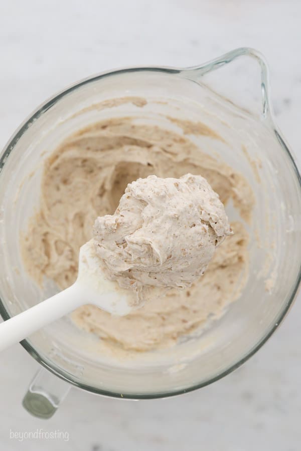 a white spatula over top of a mixing bowl with a scoop of frosting on it