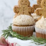 A white cake stand with gingerbread man on top of a frosted cupcakes