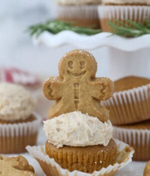 A gingerbread man on top of a frosted cupcake