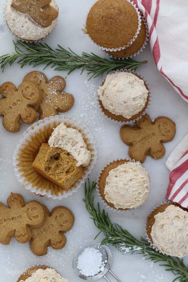 an overhead shot of gingerbread men and frosted cupcakes