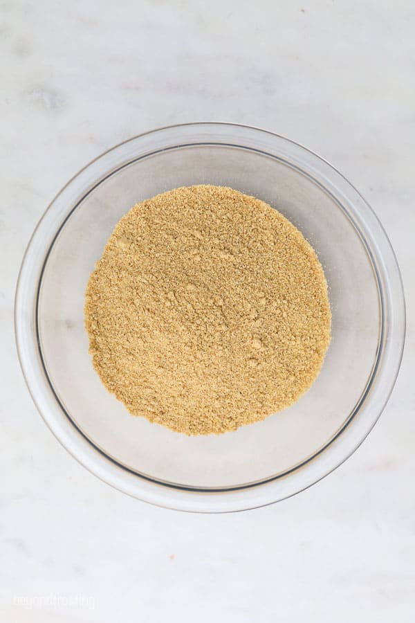 Make the best homemade graham cracker crust to use for your favorite pies, cheesecakes, and no-bake desserts. With par-baking instructions. an overhead shot of a glass bowl with graham cracker crumbs