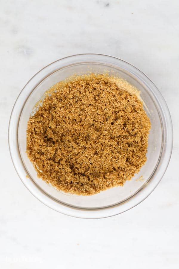 an overhead shot of a glass bowl with graham cracker crumbs mixed with butter