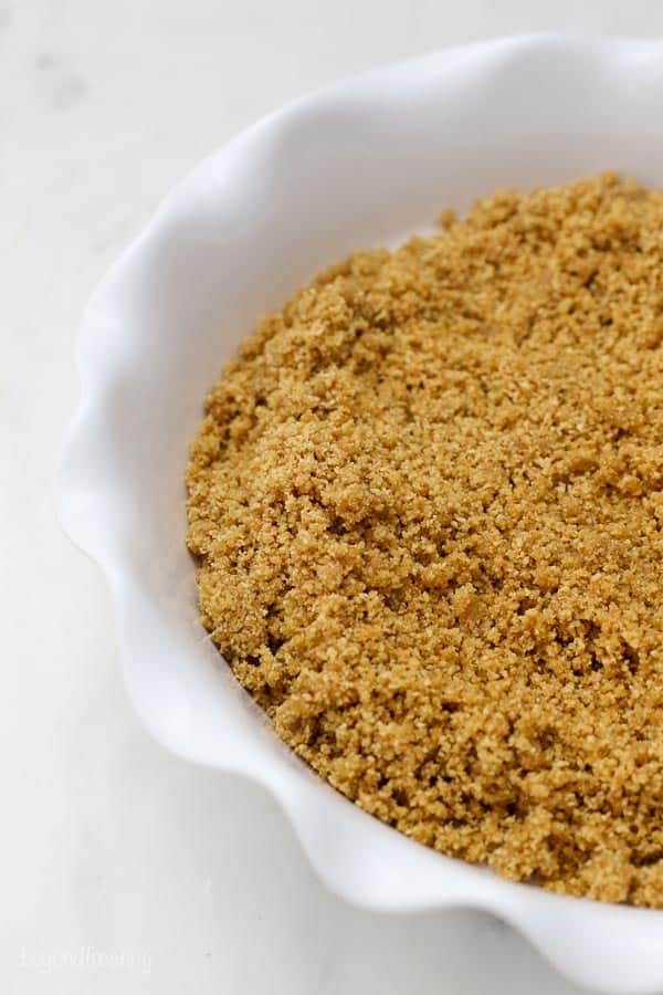 Make the best homemade graham cracker crust to use for your favorite pies, cheesecakes, and no-bake desserts. With par-baking instructions. a white pie plate filled with graham cracker crumbs