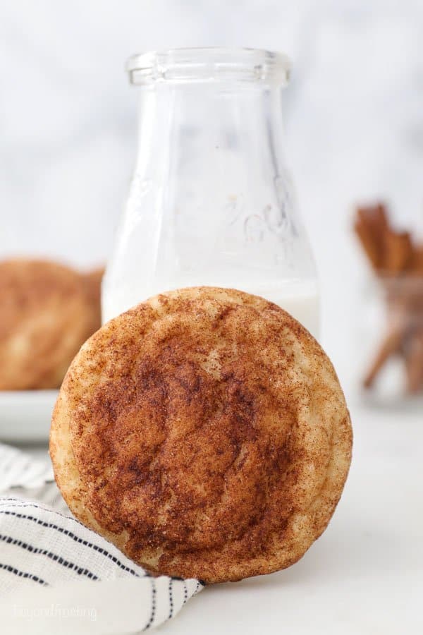 A snickerdoodle cookie leaning up against a glass milk jar
