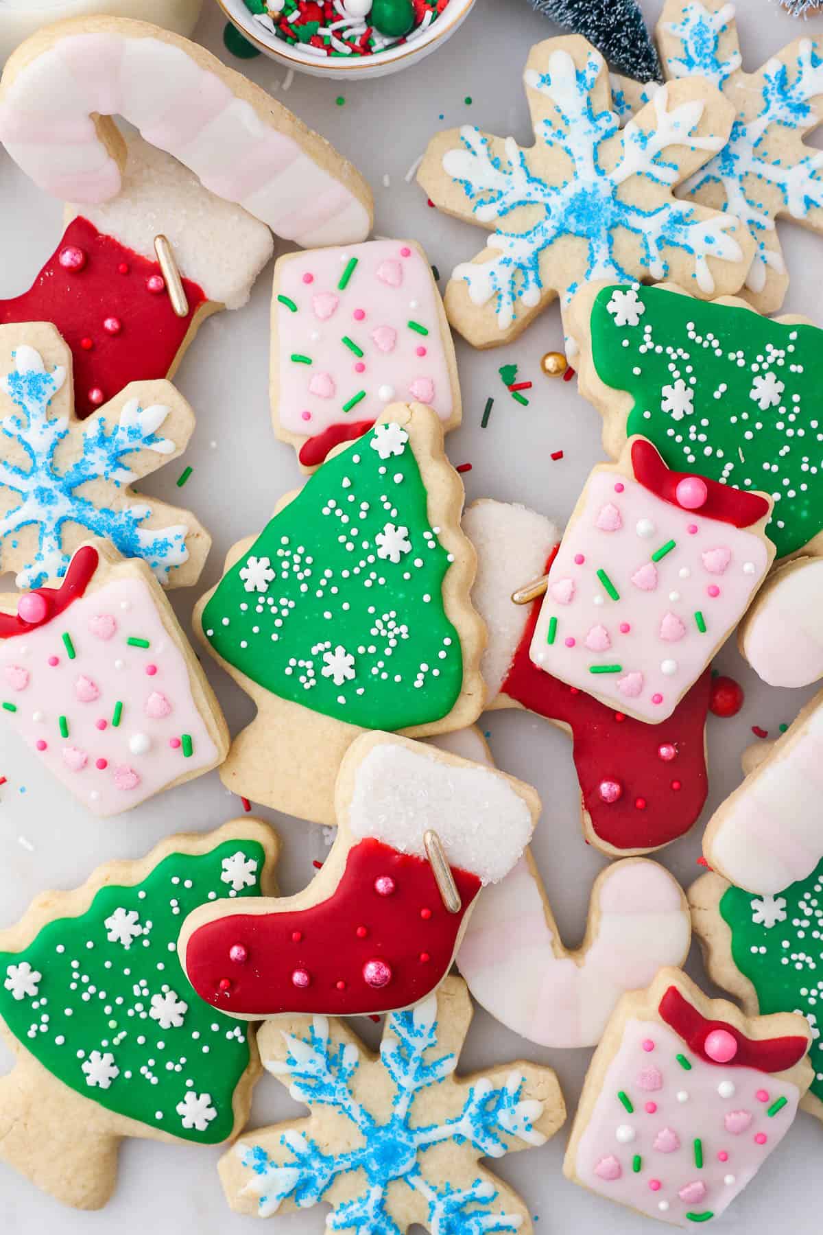 Assorted cut-out Christmas sugar cookies in the shape of stockings, trees, gifts, and snowflakes decorated with sugar cookie icing.