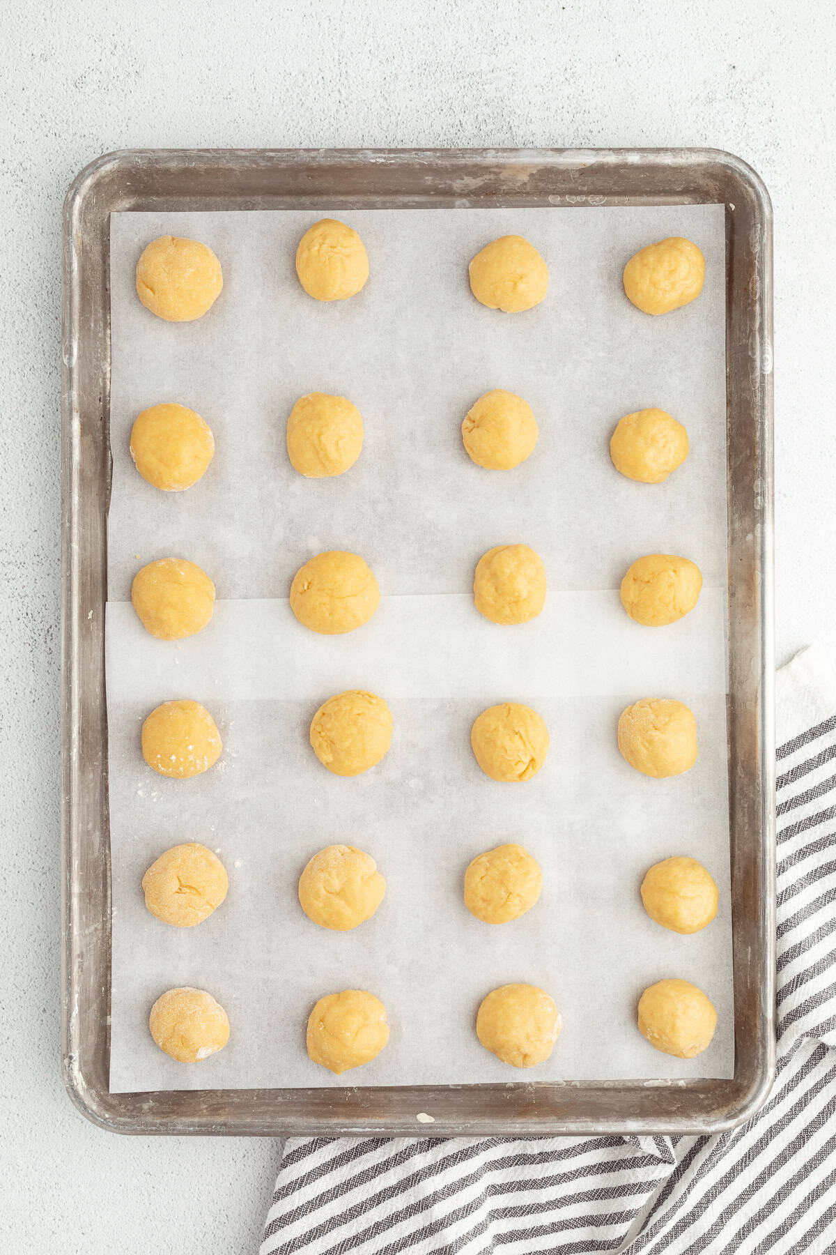 Italian anise cookies are traditional, cake-like Christmas cookies dipped in glaze and topped with sprinkles. Perfect for cookie platters! Anise cookie dough balls arranged in rows on a baking sheet.