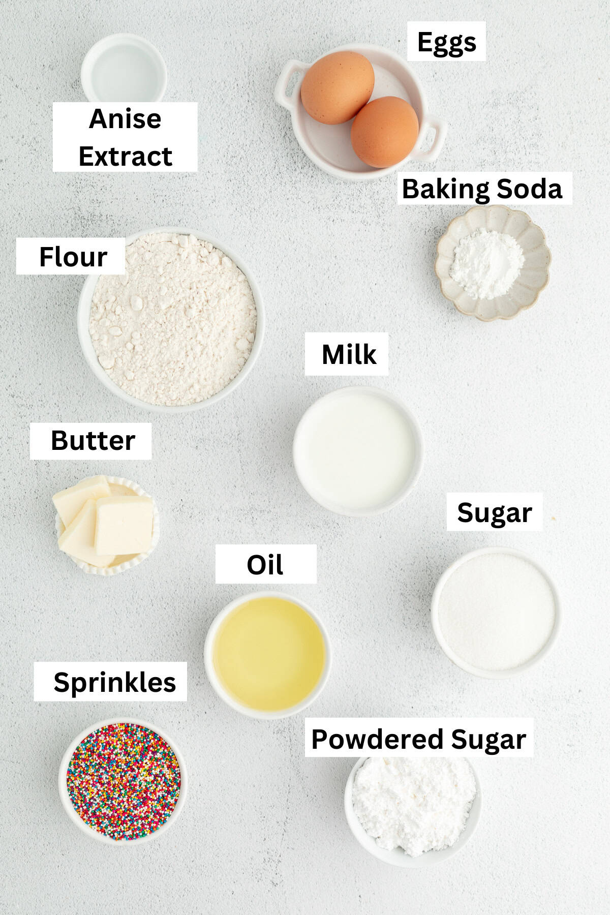 Italian anise cookies are traditional, cake-like Christmas cookies dipped in glaze and topped with sprinkles. Perfect for cookie platters! Anise cookies ingredients with text labels overlaying each ingredient.