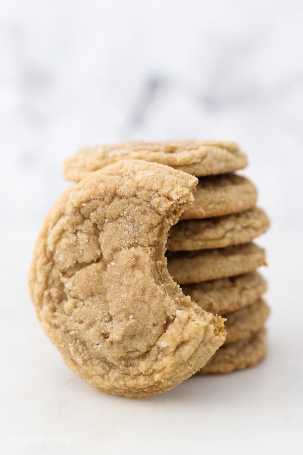 A cookie with a bite taken out of it leaning up against a stack of cookies