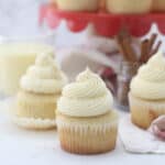 three eggnog cupcakes and a red cake stand in the background