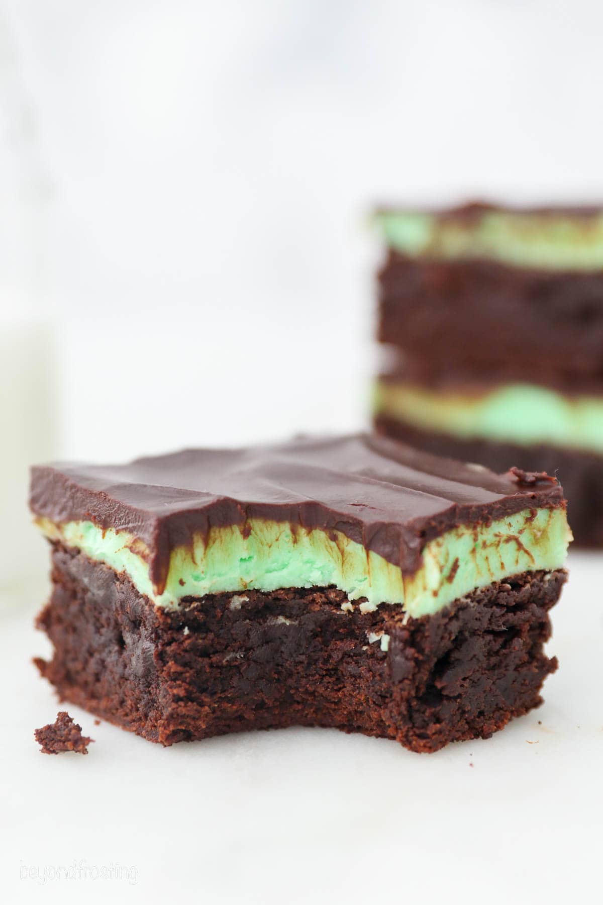A mint chocolate brownie with a bite missing on a whte countertop.
