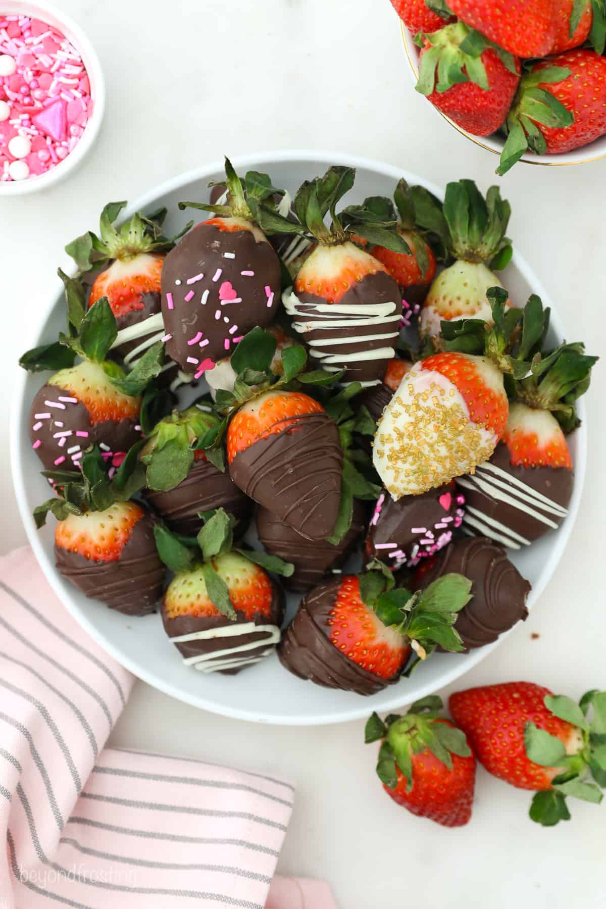 Overhead view of assorted chocolate covered strawberries arranged on a white plate.