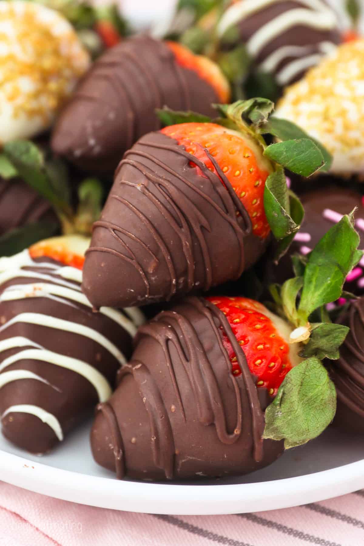 Assorted chocolate covered strawberries arranged on a white plate.