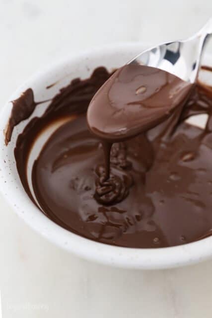 A Bowl of Melted Chocolate with Some Dripping off the Mixing Spoon