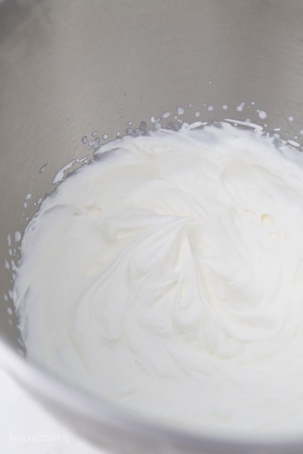 a metal mixing bowl with whipped cream