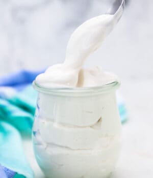 A Spoon Scooping Out a Dollop of Coconut Whipped Cream from a Glass