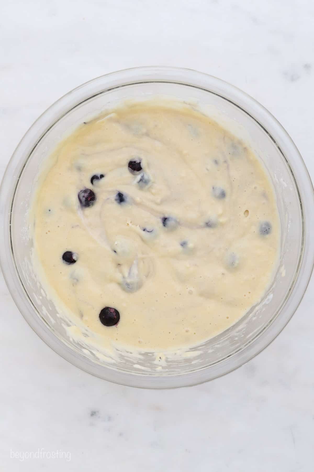 Blueberry muffin batter in a glass bowl.