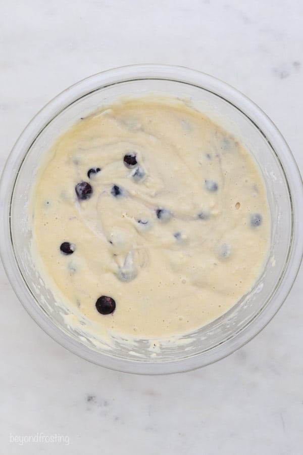 an overhead shot of a glass mixing bowl of blueberry muffin batter