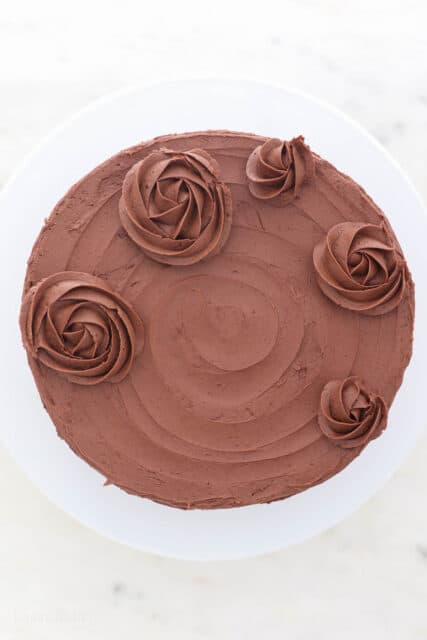 Overhead view of a frosted marble cake partially decorated with chocolate buttercream roses.