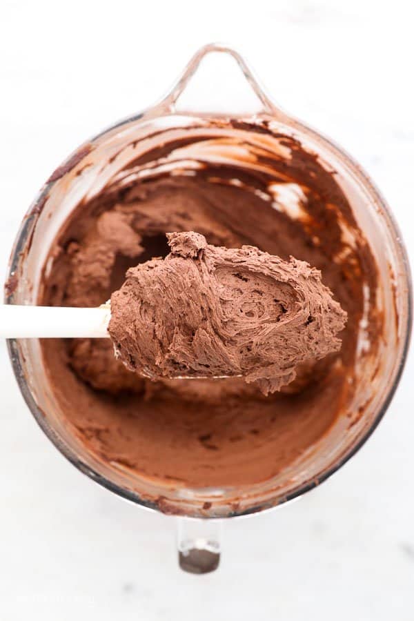 a spatula with chocolate frosting hanging over a mixing bowl