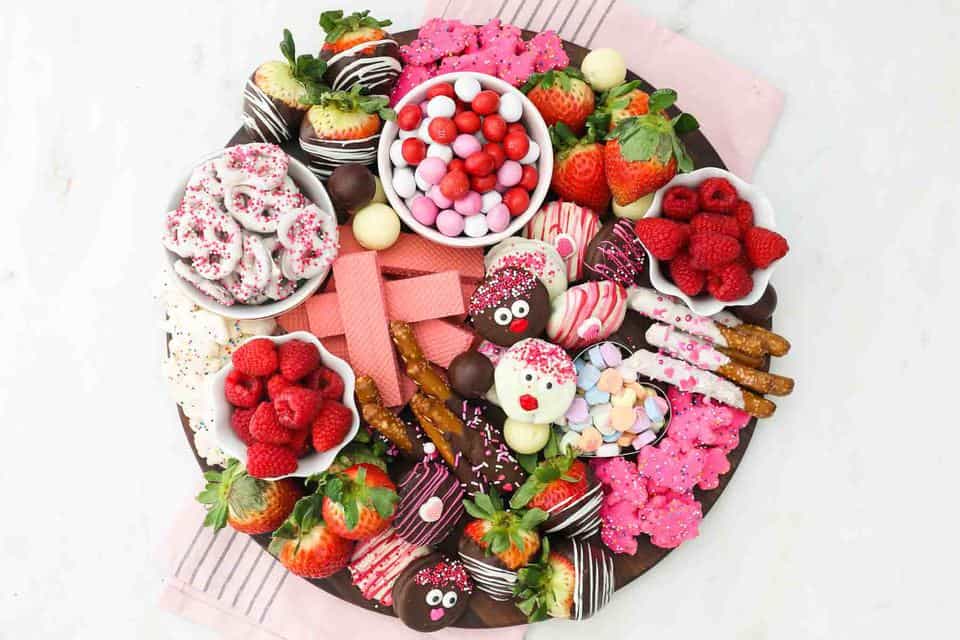 Overhead shot of a dessert charcuterie board for Valentine's day with candy, fruit and cookies and pink towel