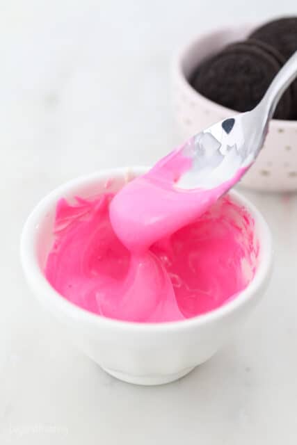 pink colored white chocolate dripping off a spoon