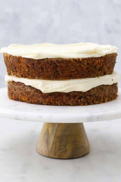 a marble cake plate with two layers of carrot cake and cream cheese frosting