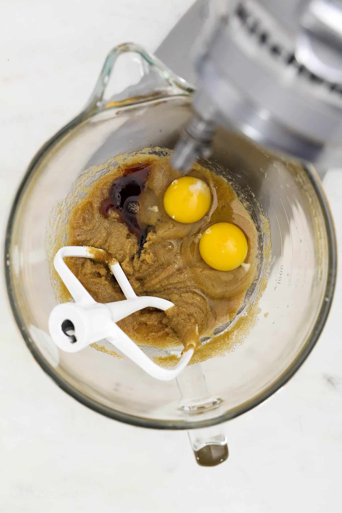 Eggs added to wet blondie batter in a mixing bowl with a stand mixer attachment.