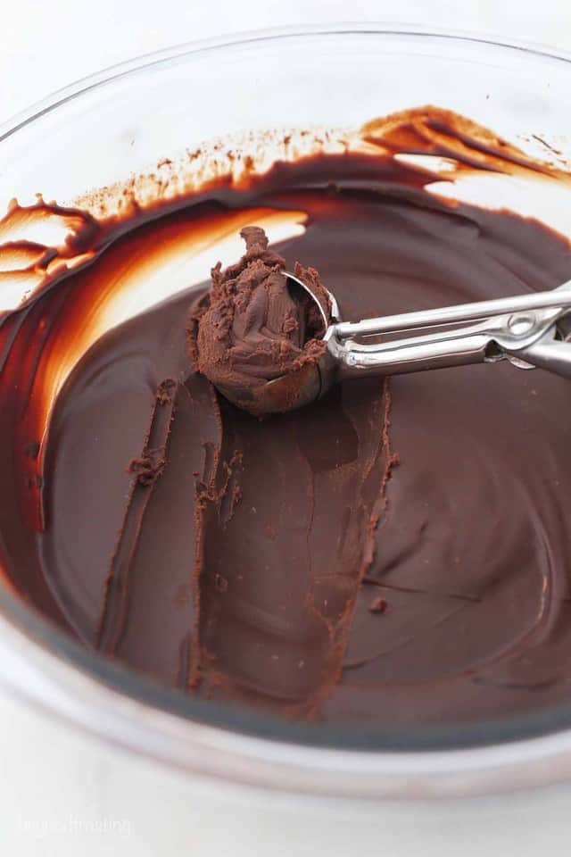 A Small Cookie Scoop Scraping Chocolate Ganache Out of a Bowl