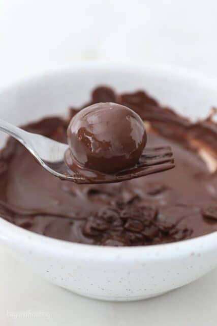 A Truffle Coated in Chocolate on a Metal Spoon