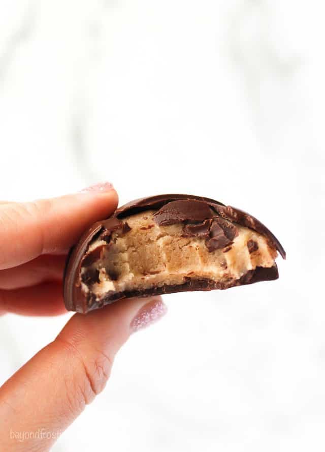 A cookie dough filled chocolate Easter egg with a bite taken out of it showing the inside of the egg
