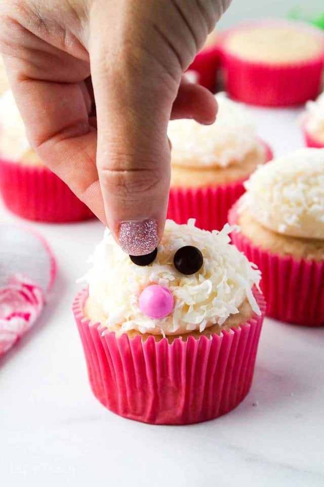 fingers adding eyes to a cupcake decorated like an easter bunny
