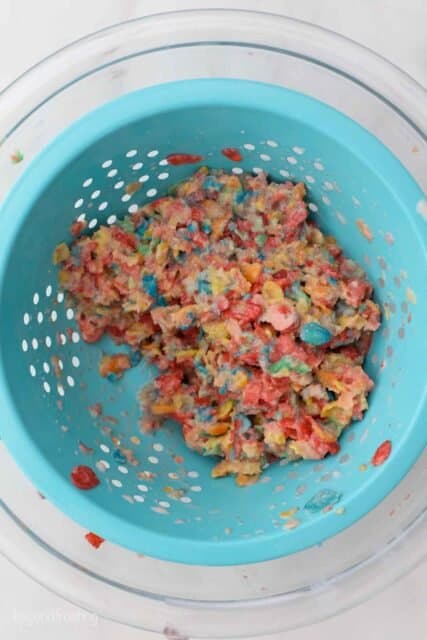 Fruity Pebble cereal in a colander that have been soaked in milk