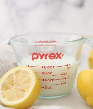 A Measuring Cup Filled with Buttermilk Next to Half of a Fresh Lemon