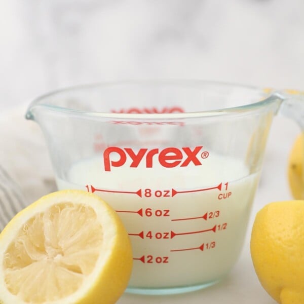 A Measuring Cup Filled with Buttermilk Next to Half of a Fresh Lemon
