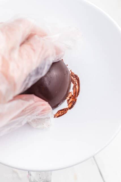 a chocolate sphere being pressed against a white plate
