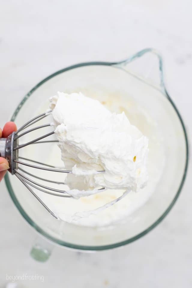 a stand mixer with a whisk full of whipped cream frosting