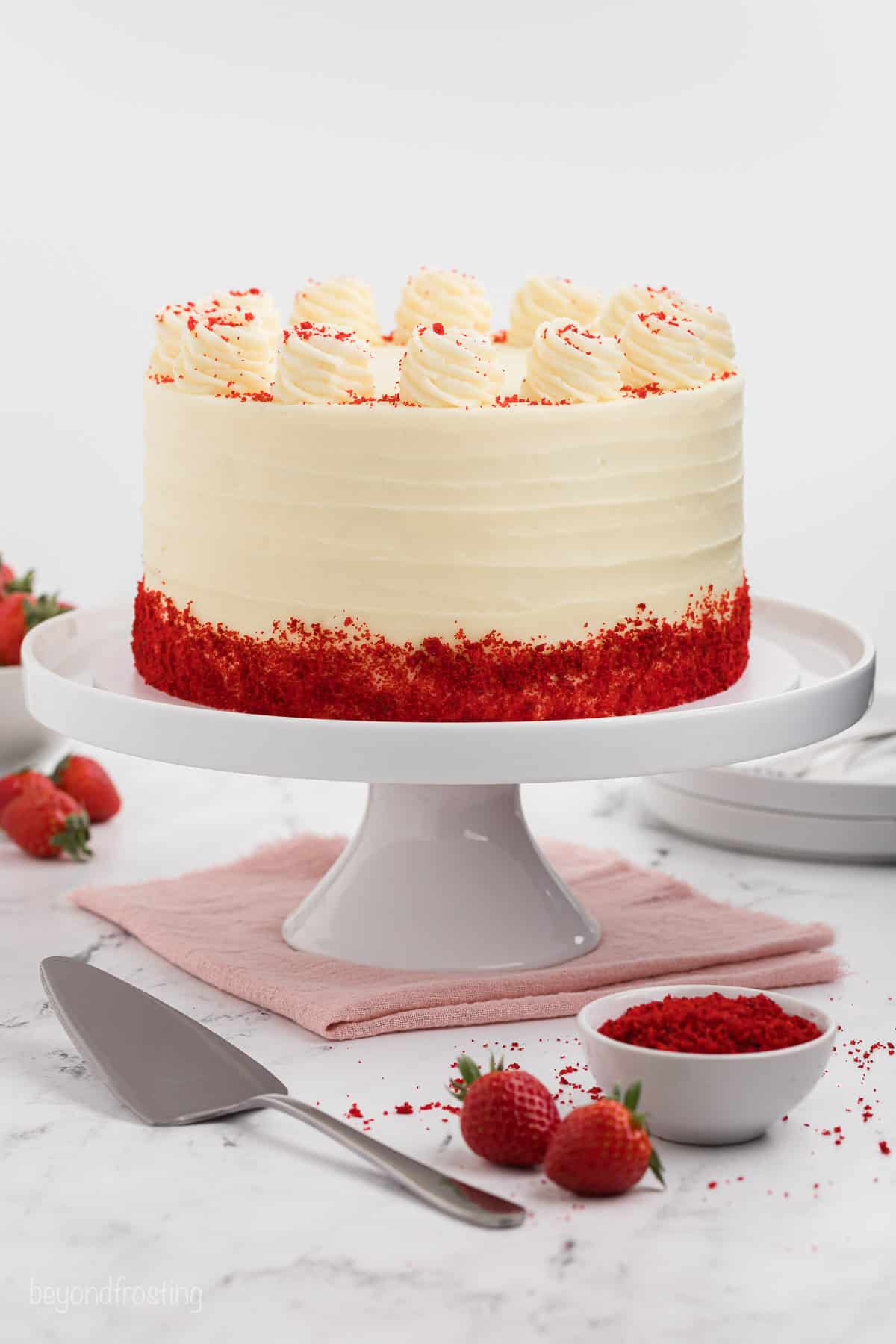 Frosted and decorated red velvet layer cake on a cake stand.