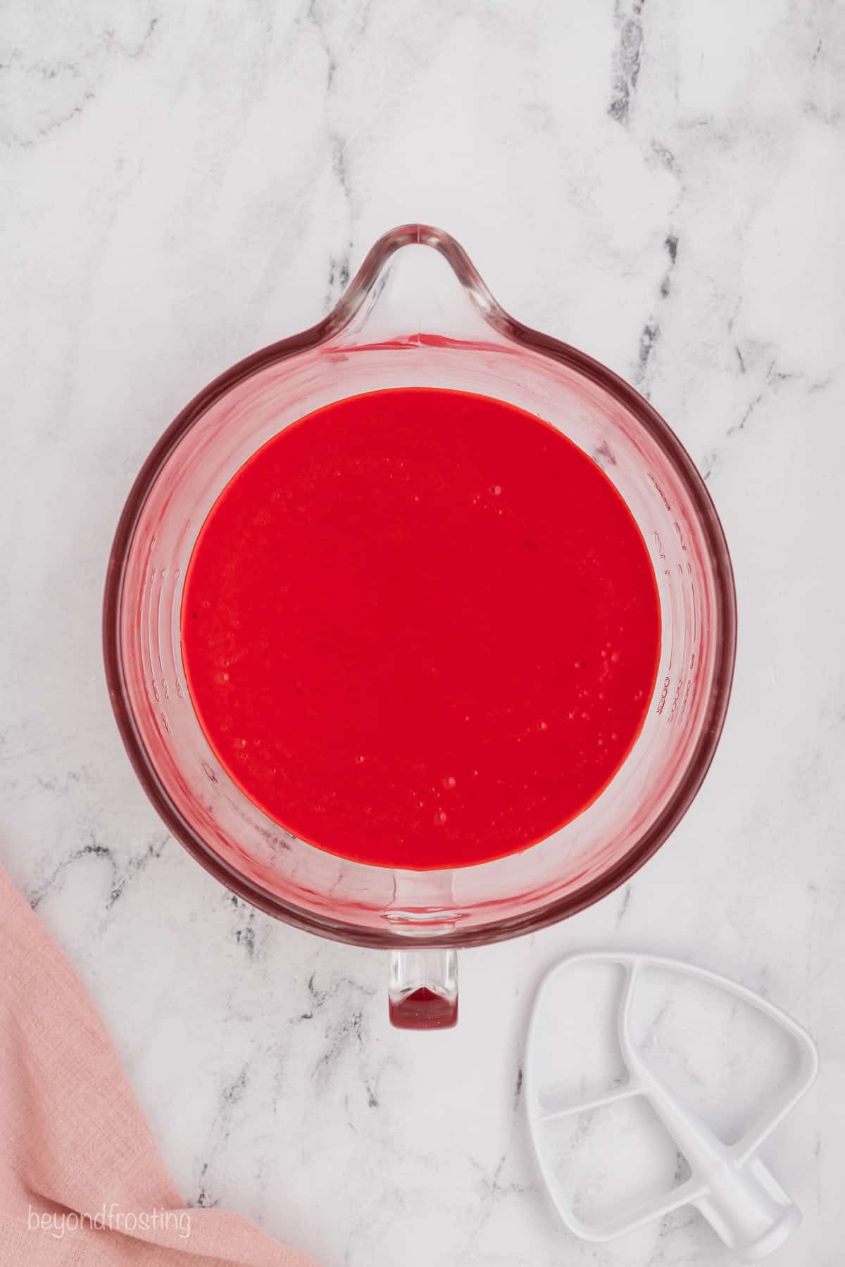 Red velvet cake batter in a glass mixing bowl.