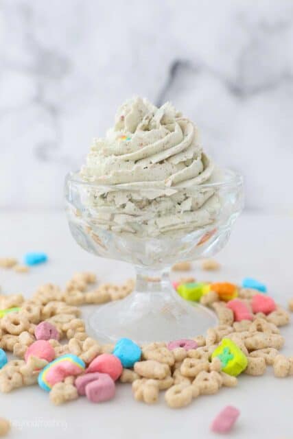 a small ice cream dish with whipped cream surrounded by Lucky Charms Cereal