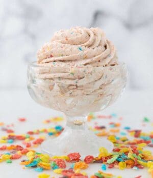 a small ice cream dish with whipped cream surrounded by Fruity Pebbles Cereal