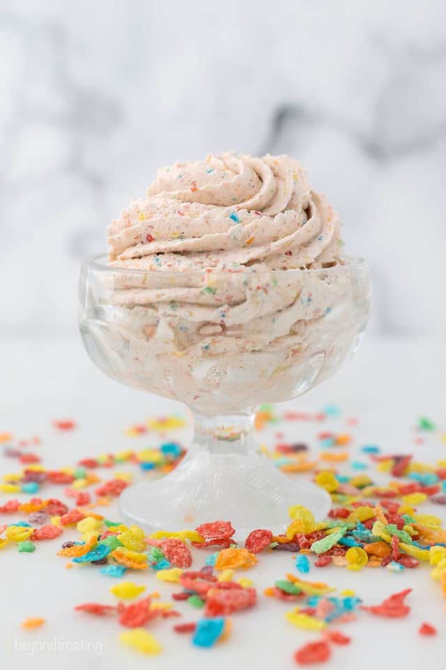 a small ice cream dish with whipped cream surrounded by Fruity Pebbles Cereal