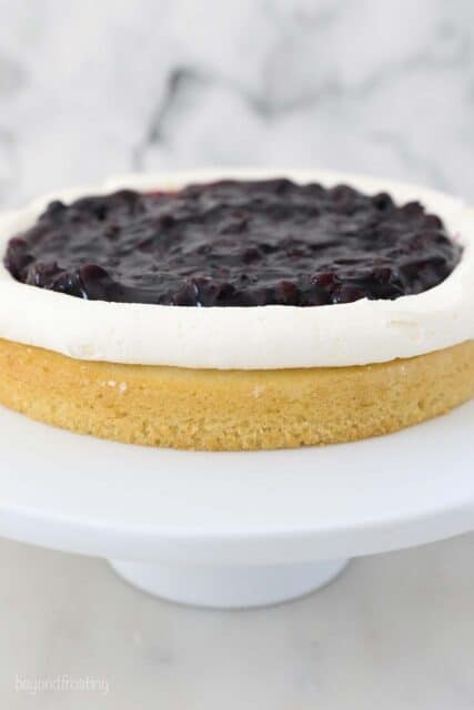a layer of cake with a boarder of frosting and blueberry pie filling in the middle