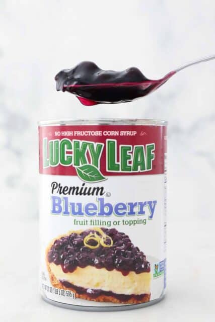 a can of Lucky Leaf blueberry pie filling and a spoon floating above it