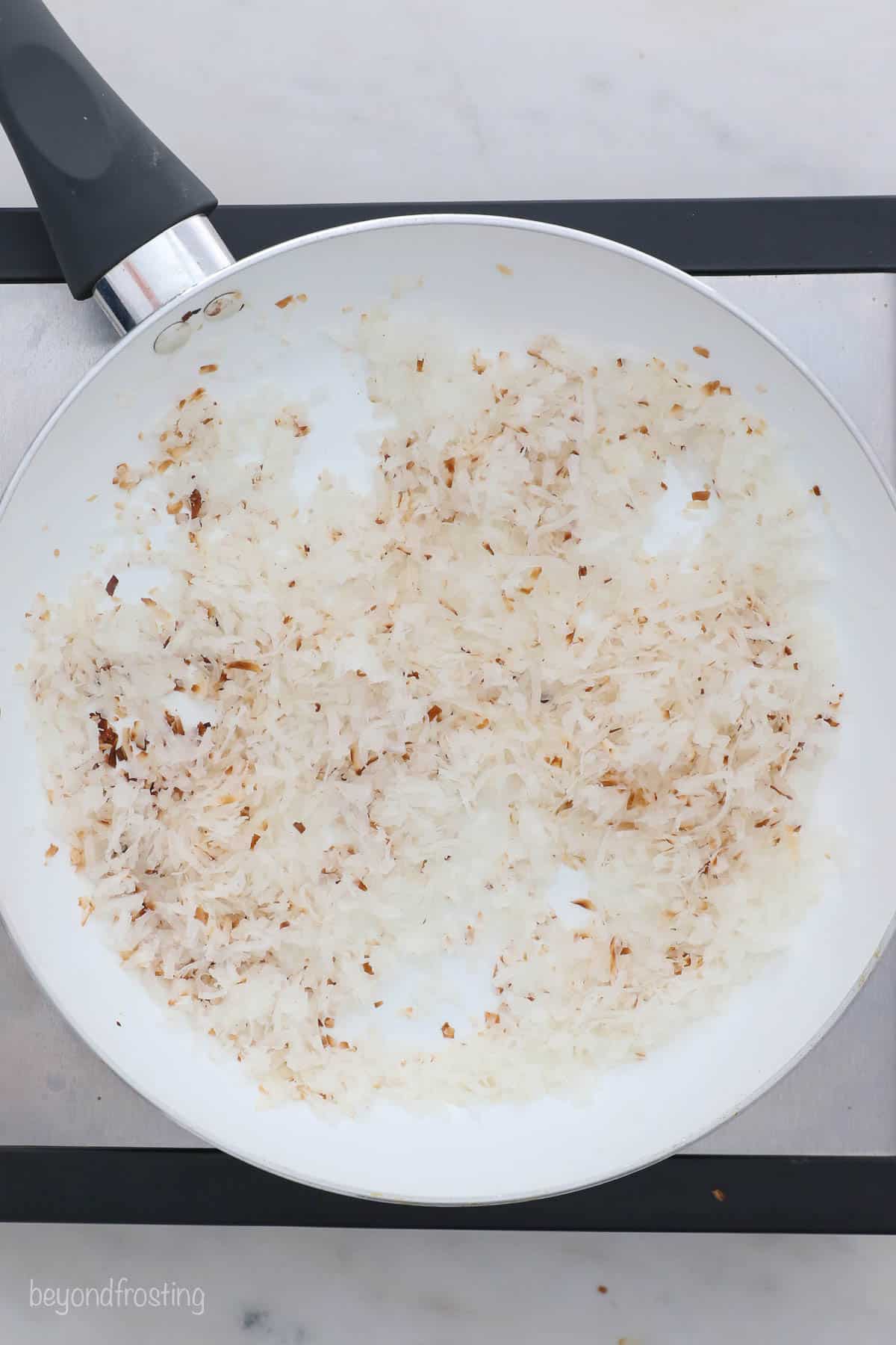 Coconut flakes in a skillet with a few browned