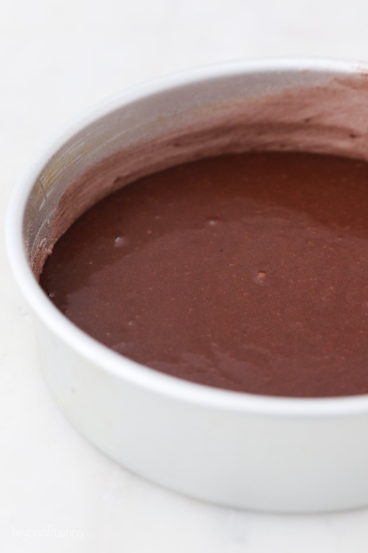 Close up of chocolate cake batter in a metal cake pan.
