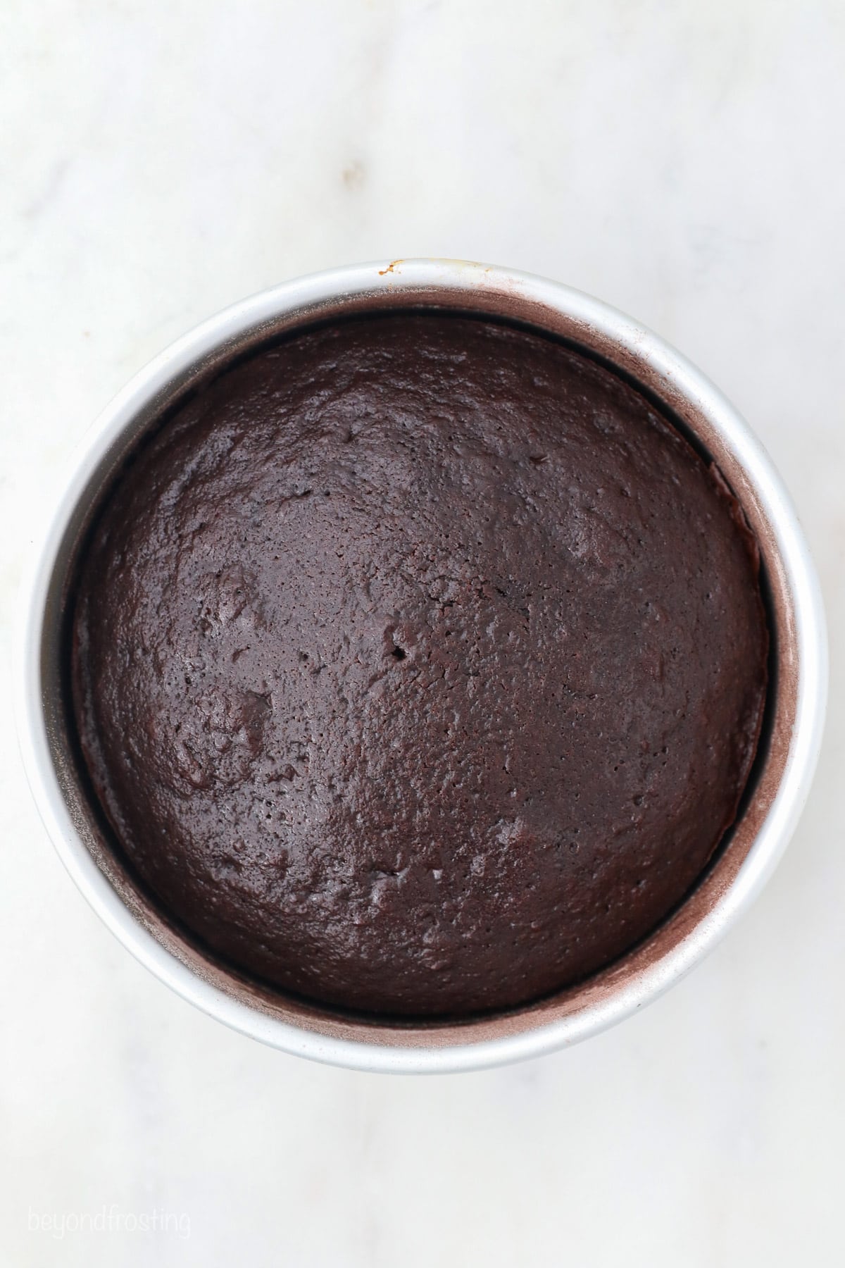 Overhead view of baked chocolate cake in a round metal cake pan.