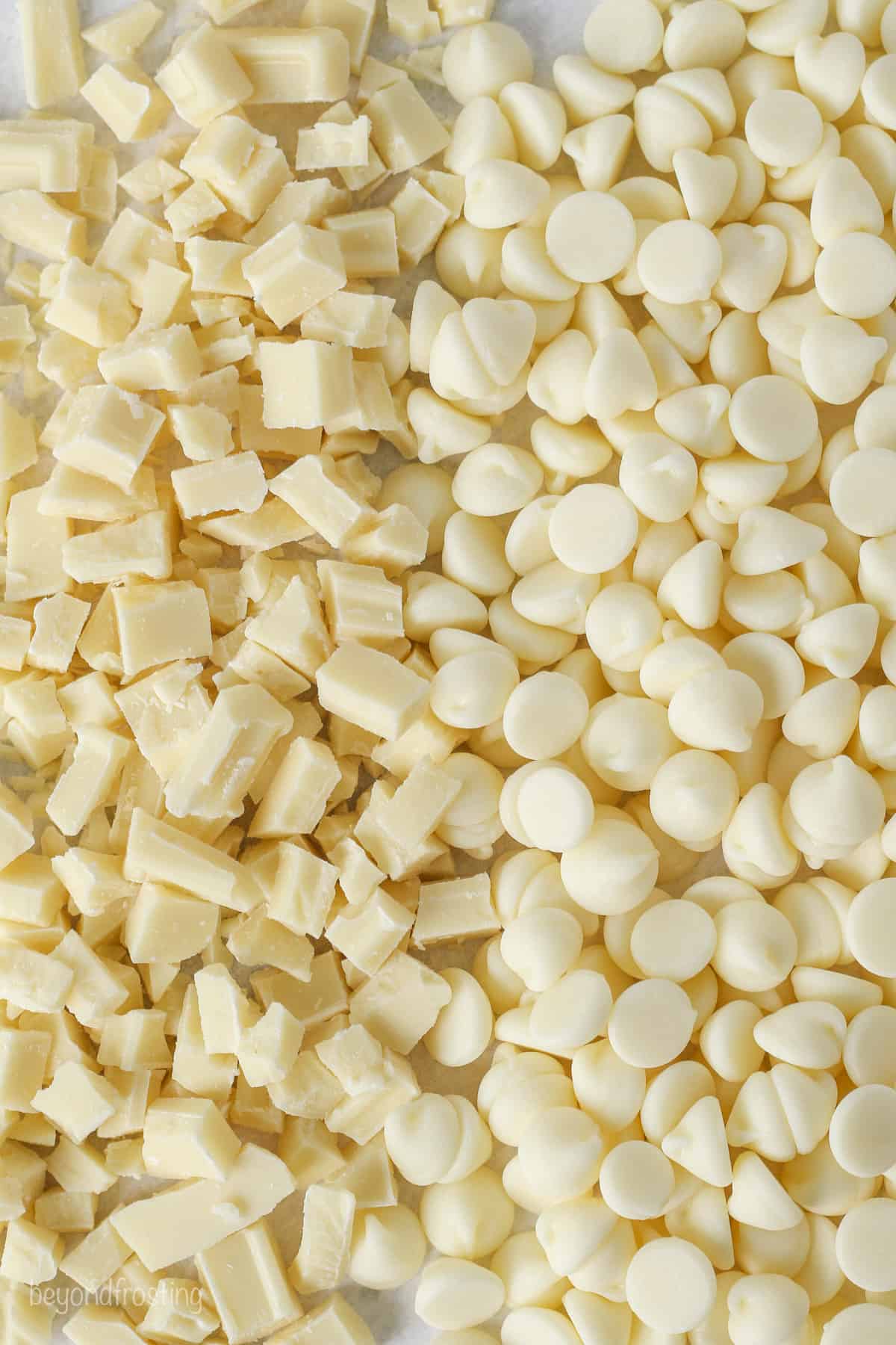 Close up view of white chocolate chips next to chopped white chocolate pieces.