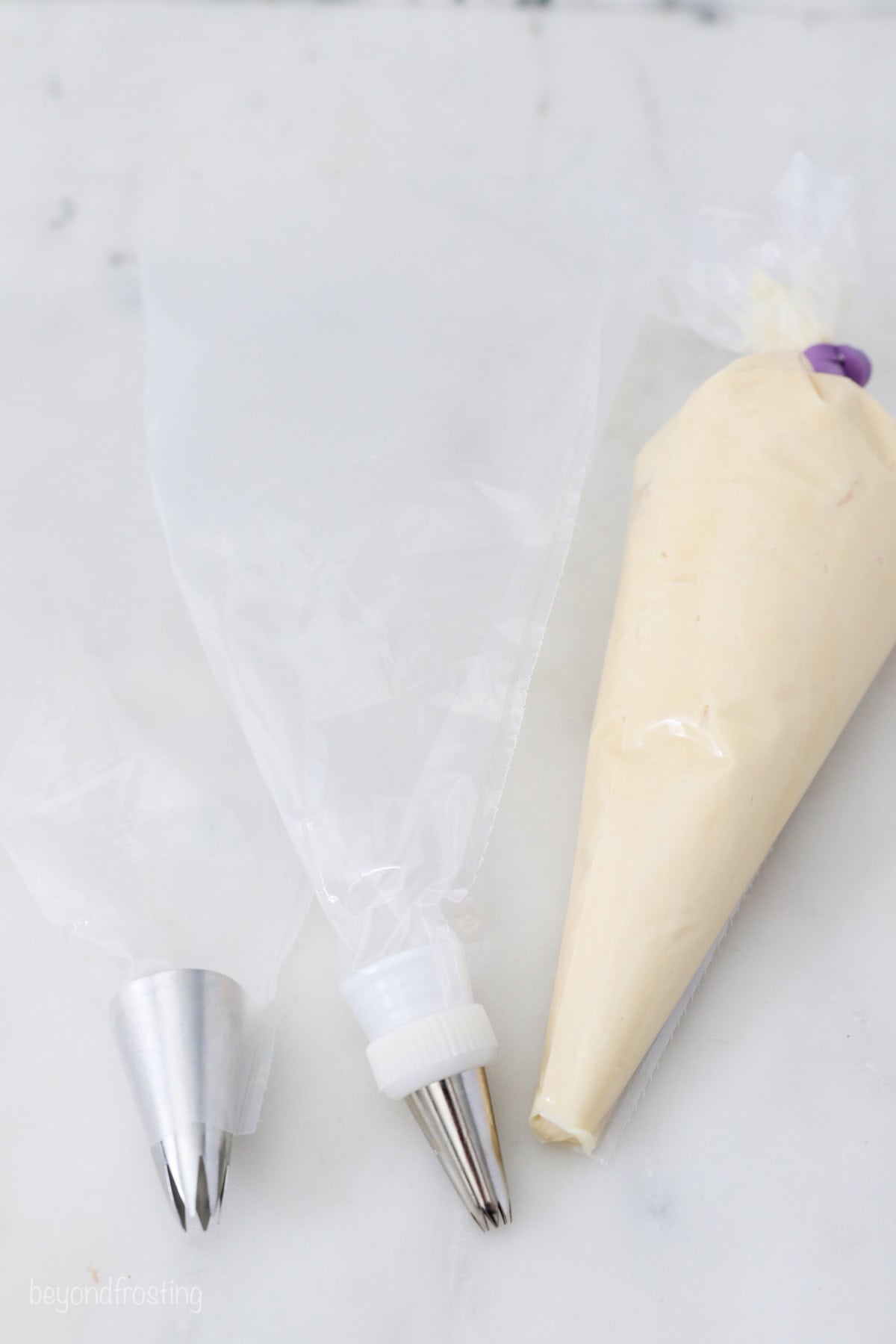 A piping tip resting next to an empty piping bag and a second piping bag filled with frosting.