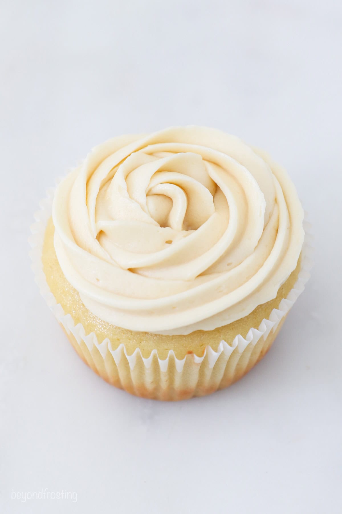 A cupcake frosted with a vanilla frosting swirl.