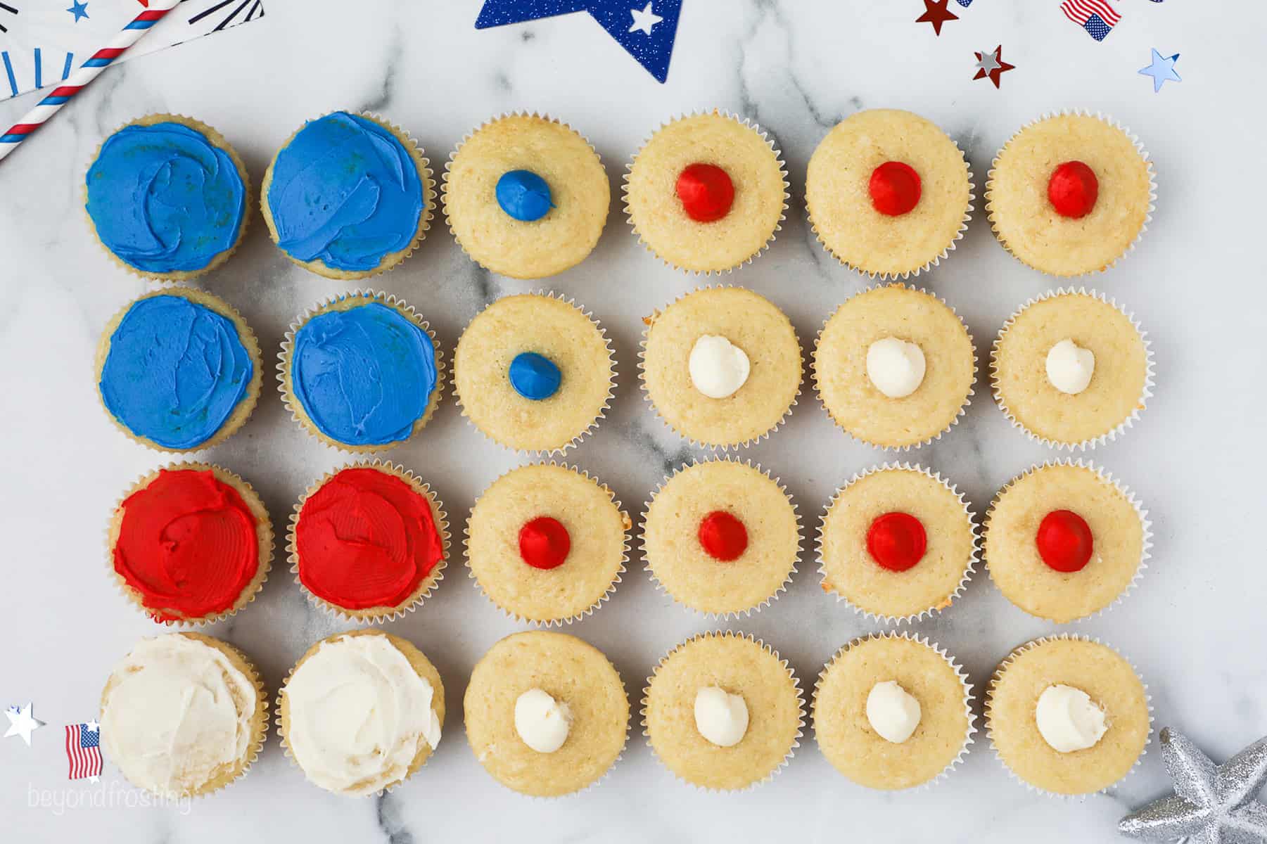 Overhead view of 24 cupcakes partially frosted with red, white, and blue frosting arranged in the shape of an American flag.